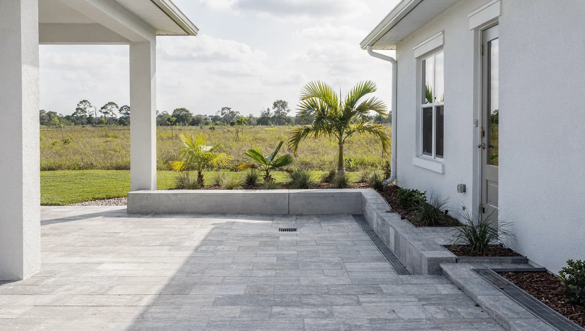 Light gray paved courtyard with a low seat wall